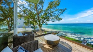 A balcony with wicker furniture, a round seating area, and a view of the ocean.