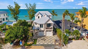 A beachfront property with a two-story house, a covered patio, and a view of the ocean.