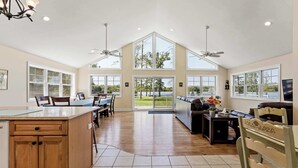 A spacious kitchen with a large island, dining area with chairs, and a view of a lake through large windows. - Vast Lakefront Home with Rec Room and Fire Pit (Pullman)