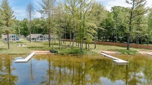 A serene lakeside property with a dock, a grassy lawn, and a wooden fence. - Vast Lakefront Home with Rec Room and Fire Pit (Pullman)