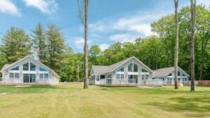 A row of three single-story houses with large windows and a grassy yard. - Vast Lakefront Home with Rec Room and Fire Pit (Pullman)