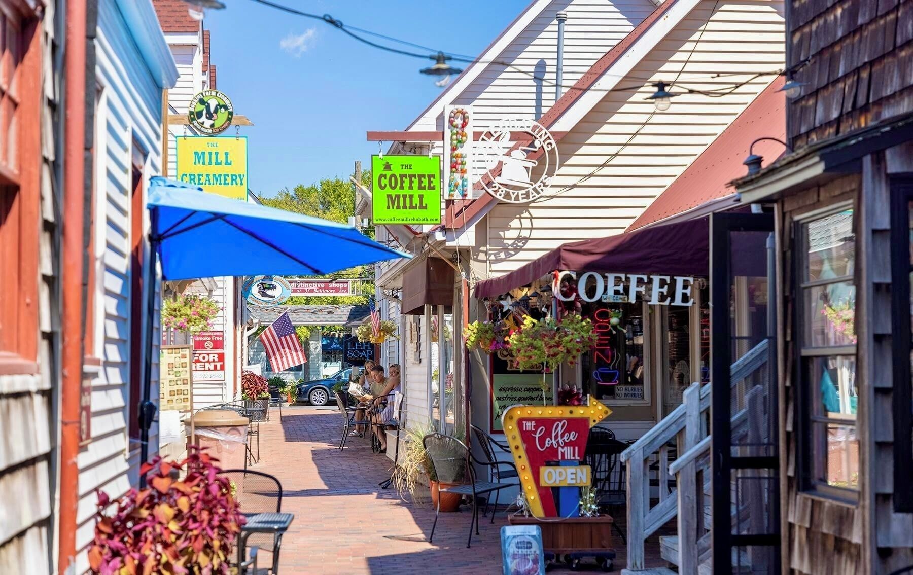A narrow street with shops, including a coffee mill and a creamery.