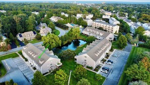 An aerial view of a residential area with multiple two-story houses, a central pond, and a parking lot. - Luxury 4BR Townhouse, 2 Primary Bedrooms, east of route 1, POOL,  close to beach (Rehoboth Beach)