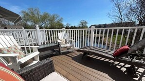 A deck with outdoor furniture, a white railing, and a view of a body of water and houses in the background. - Luxury 4BR Townhouse, 2 Primary Bedrooms, east of route 1, POOL,  close to beach (Rehoboth Beach)