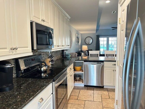 A kitchen with white cabinets, a microwave, a stove, a dishwasher, and a refrigerator.