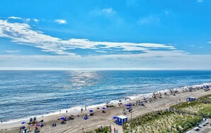 A beach with umbrellas, a lifeguard tower, and a clear view of the ocean.