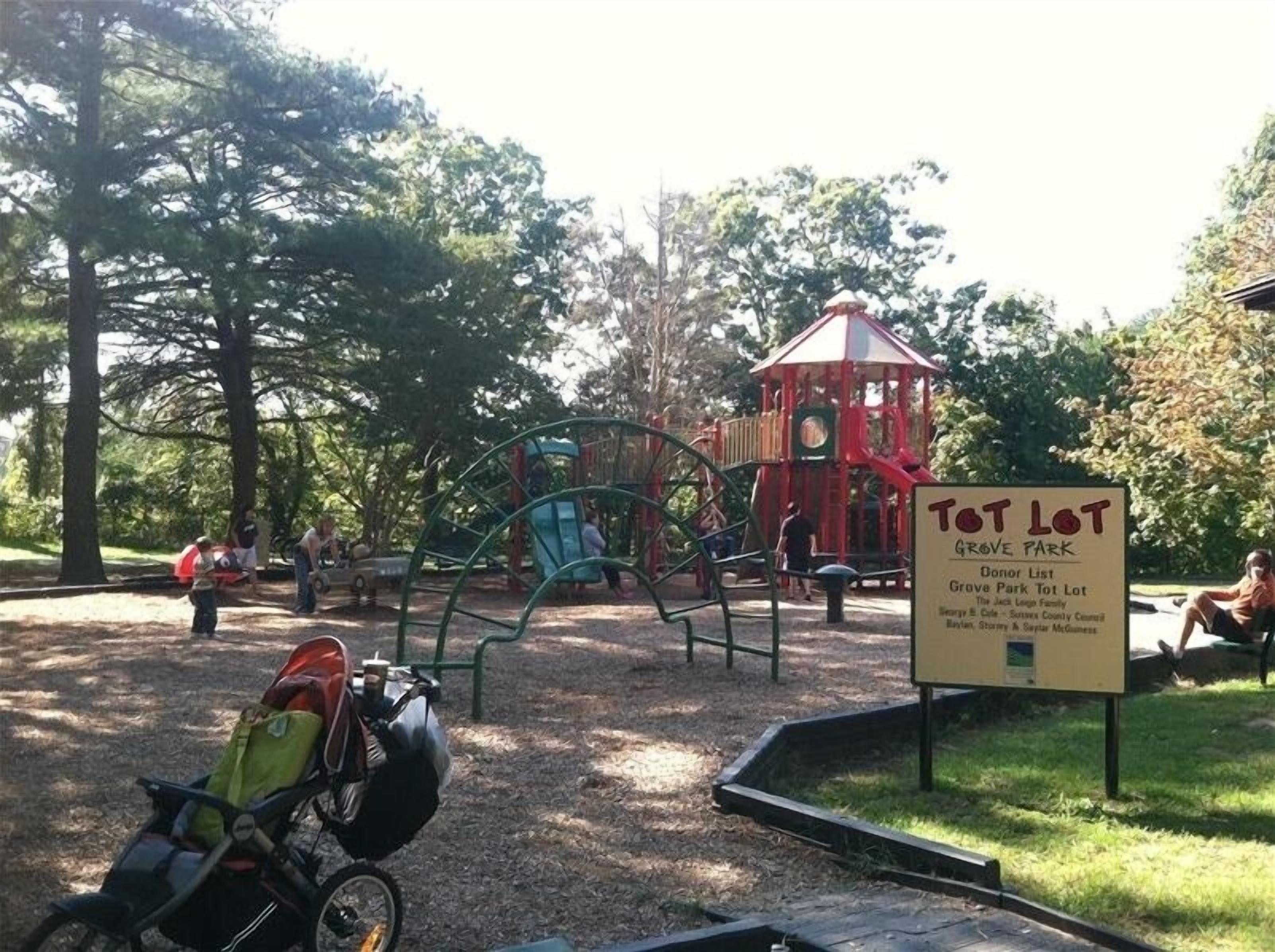 Une aire de jeux dotée de diverses installations et d’un panneau indiquant la présence d’un espace de jeux pour les tout-petits au parc de Grove.