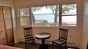 Une pièce avec vue sur un lac, deux chaises, une petite table et une porte en bois.