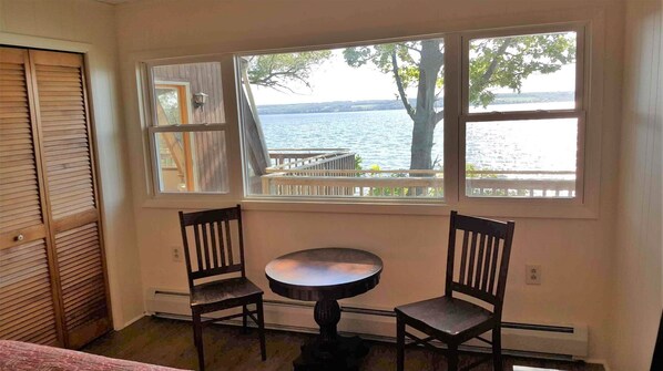 A room with a view of a lake, two chairs, a small table, and a wooden door. - Family fun, wine tours and beautiful sunsets (Romulus)