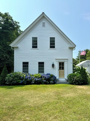 A white two-story house with a front door, two windows, and a small porch.