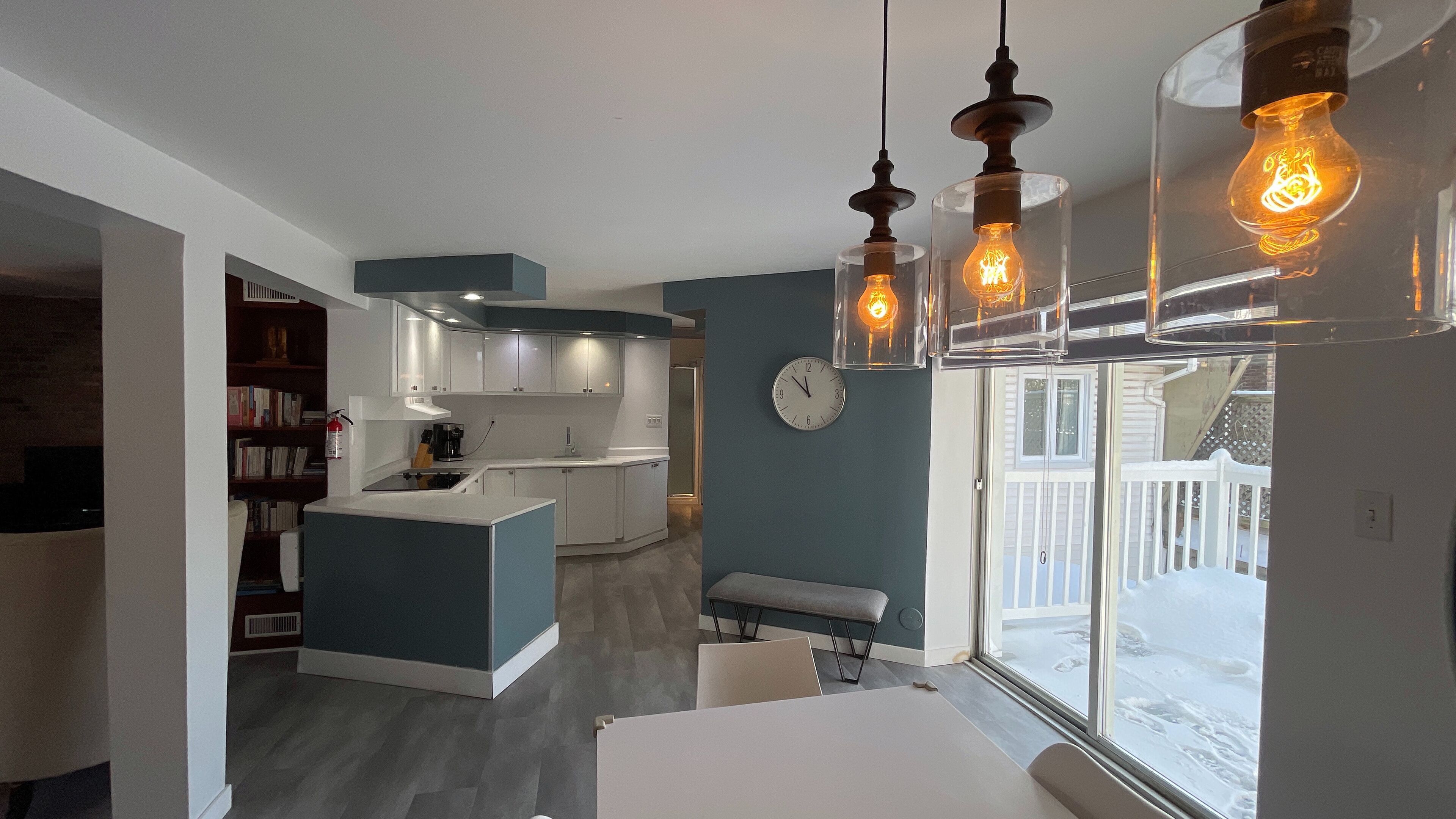 A modern kitchen with white cabinets, a central island, and pendant lighting.