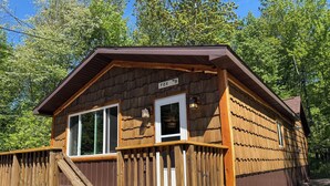 A wooden cabin with a porch, a staircase, and a sign indicating it is room #9. - Spacious 2 Bedroom Cabin @ Northwoods Resort (AuTrain)