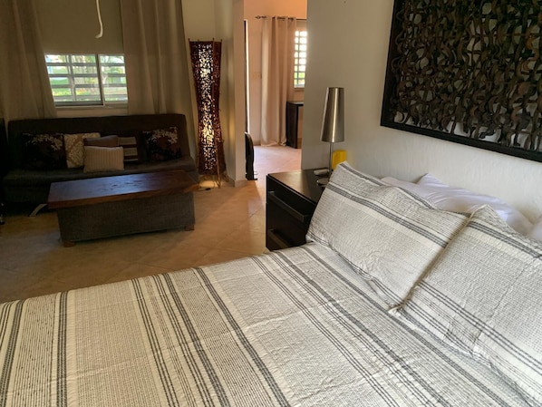 Ein Schlafzimmer mit Bett, Sofa, Nachttisch und Lampe.