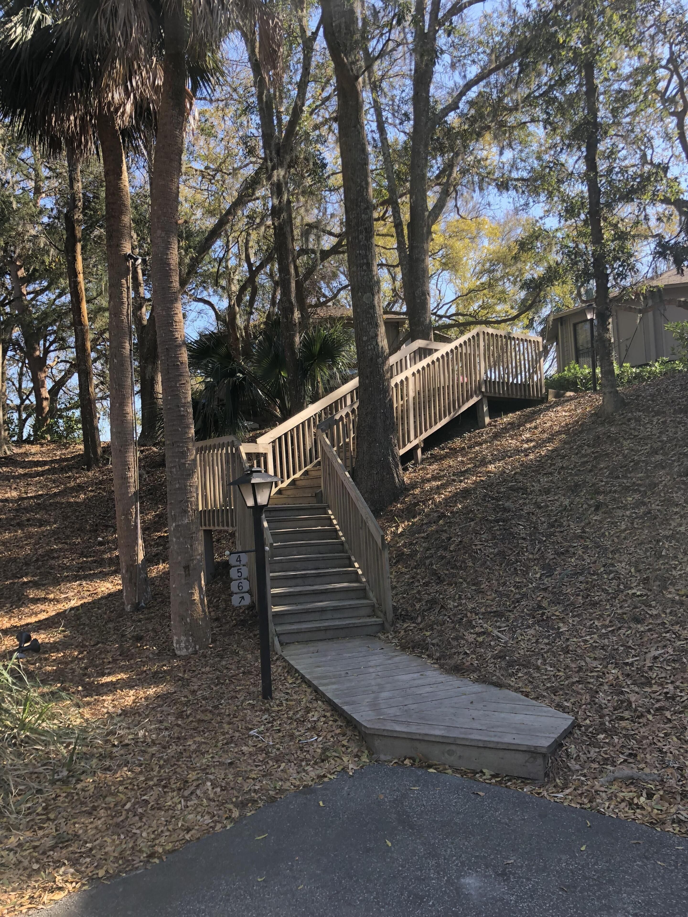 A wooden staircase leading up a hill, surrounded by trees and a clear sky.