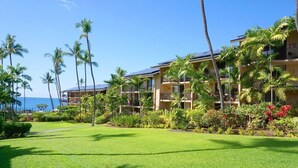 A hotel with multiple balconies, lush green lawns, and palm trees.