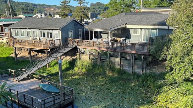 Une maison avec une jetée qui s’avance sur un étang où flottent des nénuphars.