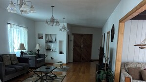 Un salon spacieux doté d’un parquet, d’un canapé, d’une table basse et d’un lustre.