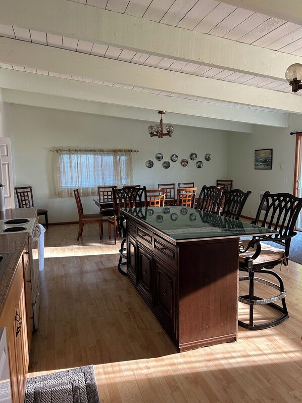 A spacious dining area with a pool table, wooden chairs, and a chandelier.