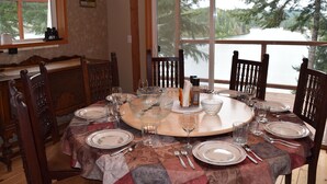 Une table à manger dressée pour six personnes, avec vue sur un lac.