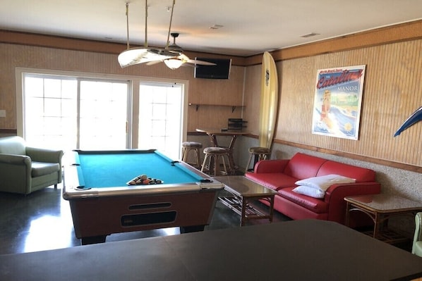 A pool table, a red sofa, and a poster on the wall.