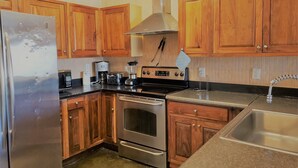 A kitchen with wooden cabinets, stainless steel appliances, and a granite countertop. - In the HEART of North Myrtle Beach (North Myrtle Beach)