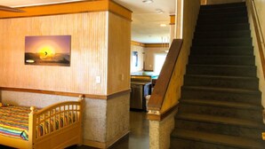 A hotel room with a wooden bed, a painting of a sunset, a staircase, and a kitchen area in the background. - In the HEART of North Myrtle Beach (North Myrtle Beach)