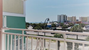 A balcony with a view of a parking lot, palm trees, and high-rise buildings in the background. - In the HEART of North Myrtle Beach (North Myrtle Beach)