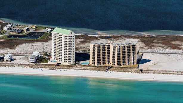 Un hôtel situé sur la côte, composé de plusieurs immeubles de grande hauteur, avec une plage et un port de plaisance.