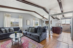 A modern living room with a sofa, coffee table, and a view of the kitchen.