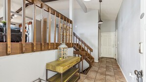 Un escalier avec des rampes en bois, une console en bois dotée de tiroirs, une lanterne et un présentoir en métal.