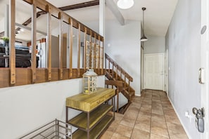 A staircase with wooden railings, a wooden console table with drawers, a lantern, and a metal rack.