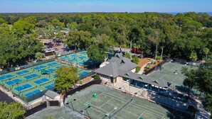 An aerial view of a tennis facility with multiple courts, surrounded by dense greenery and a clear sky. - Villa; 5 minute walk to Palmetto Dunes Beach with a Great Golf Course View!! (Hilton Head Island)