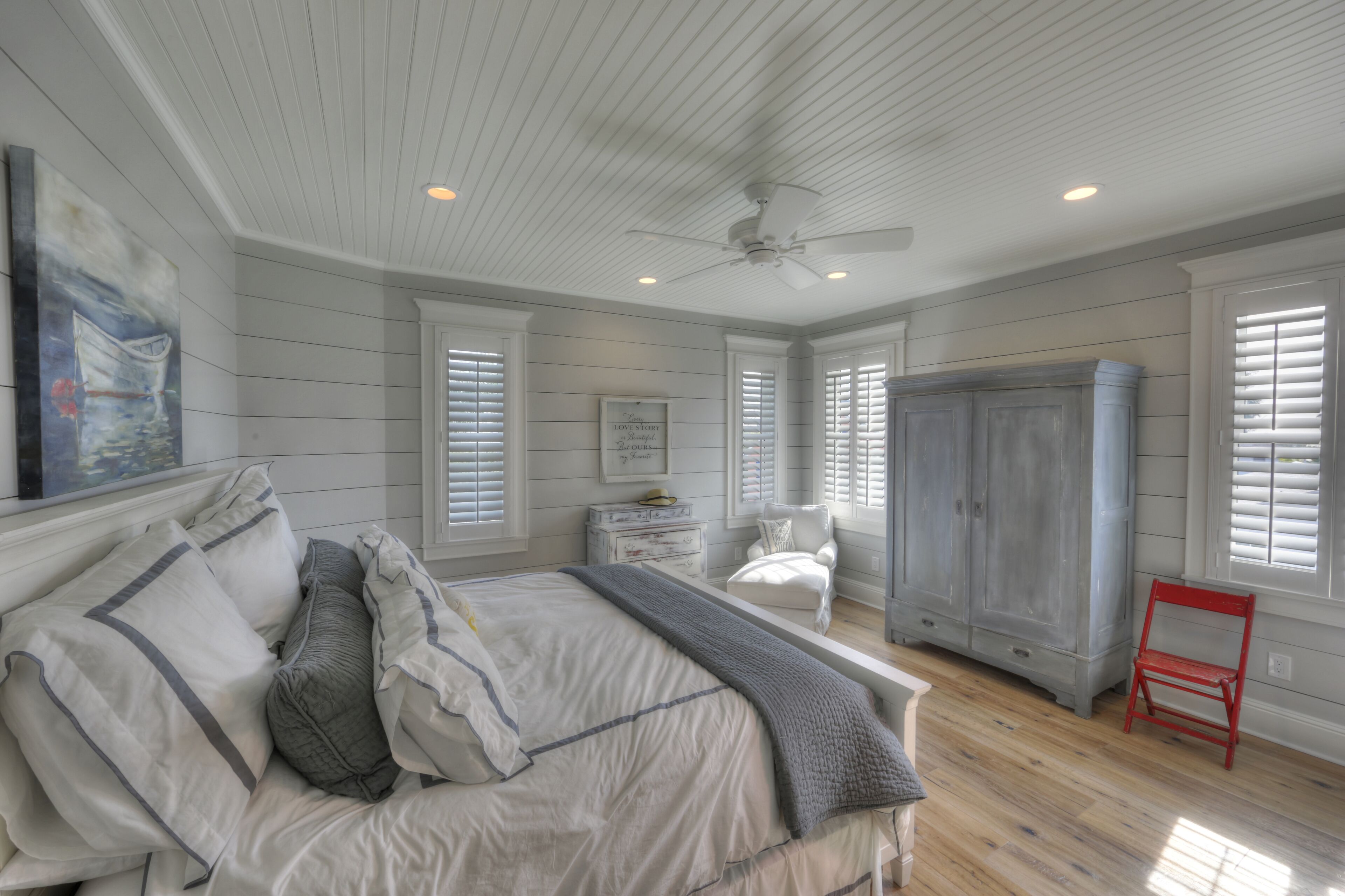 Une chambre à coucher avec un lit, une chaise, une armoire et un tableau accroché au mur.