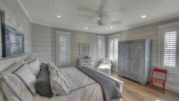 Une chambre à coucher avec un lit, une chaise, une armoire et un tableau accroché au mur.