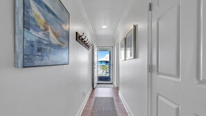 A hallway with a wooden floor, white walls, and a large abstract painting on the left.