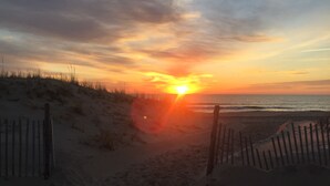 Ein Strandbild mit Sonnenuntergang, Sandweg und Holzzaun.