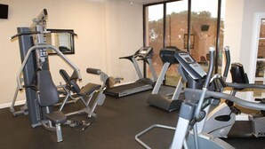A gym with various exercise machines, including treadmills and weight machines, and a large window providing a view of the outdoors. - Inquiries are Beginning for Spring and Summer. Hear the Waves from  the Balcony. (Gulf Shores)