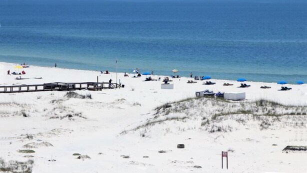 A beach with a wooden boardwalk, sandy dunes, and beach umbrellas. - Inquiries are Beginning for Spring and Summer. Hear the Waves from  the Balcony. (Gulf Shores)