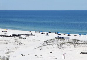 A beach with a wooden boardwalk, sandy dunes, and beach umbrellas. - Inquiries are Beginning for Spring and Summer. Hear the Waves from the Balcony. (Gulf Shores)