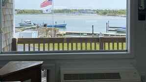 Ein Zimmer mit großem Fenster mit Blick auf einen Yachthafen, wo Boote und eine amerikanische Flagge zu sehen sind.
