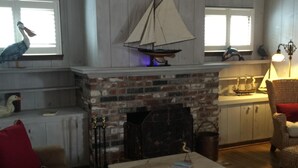 A cozy living room with a fireplace, a wooden ceiling, and a window with a bird decoration. - Steps To Carmel Beach, in the golden rectangle. The perfect location! (Carmel-by-the-Sea)