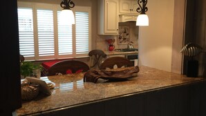 A kitchen with granite countertops, white cabinets, and pendant lighting. - Steps To Carmel Beach, in the golden rectangle. The perfect location! (Carmel-by-the-Sea)