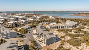 Ett bostadsområde vid kusten med moderna lägenhetsbyggnader, en strand och en klar himmel.