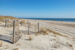 Ein Sandstrand mit hölzernen Zäunen und Schildern.
