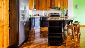 A kitchen with wooden cabinets, a stainless steel refrigerator, a built-in oven, and a granite countertop. - 2B / 2B IMPRESSIVE LAKE ARENAL, 3 POOLS, FULL KITCHEN (Tilaran)