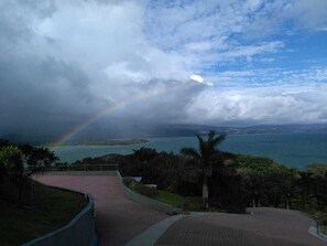 A paved pathway leading to a scenic overlook with a view of a body of water and a rainbow. - 2B / 2B IMPRESSIVE LAKE ARENAL, 3 POOLS, FULL KITCHEN (Tilaran)