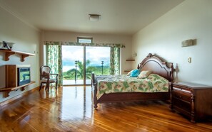 A bedroom with a wooden bed, a wooden dresser, a chair, and a television on a wooden stand. - 2B / 2B IMPRESSIVE LAKE ARENAL, 3 POOLS, FULL KITCHEN (Tilaran)