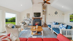 A spacious living room with a fireplace, comfortable seating, and a large television. - Manzanita Oregon beach house (Nehalem)