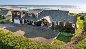 A two-story house with a garage, a covered porch, and a view of the beach. - Manzanita Oregon beach house (Nehalem)
