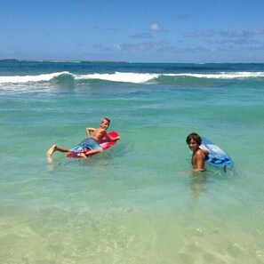 Two people lying on surfboards in shallow water.